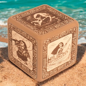 May include: A brown wooden cube with intricate carvings depicting scenes from the Disney movie Moana. The cube features images of Moana sailing on a boat, Maui with a fish hook, and Moana with the ocean.