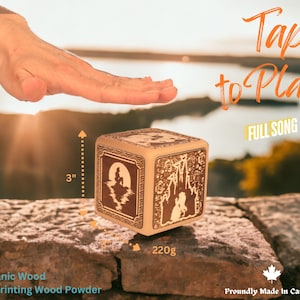 May include: A wooden music box with a 3D printed design of a castle and a mermaid. The box is 7.6 cm tall and weighs 220 grams. The text "Tap to Play FULL SONG" is printed on the box. The box is made of organic wood and is proudly made in Canada.