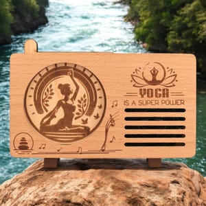 K&ouml;nnte beinhalten: Ein Holzlautsprecher mit einem Yoga-Posen-Design und dem Text "Yoga is a super power".