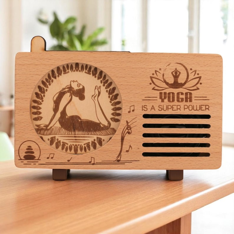 K&ouml;nnte beinhalten: Eine Holzkiste in Radioform mit einem lasergravierten Design. Das Design zeigt eine Frau in einer Yoga-Pose, eine Lotusblume und den Text "Yoga is a super power".