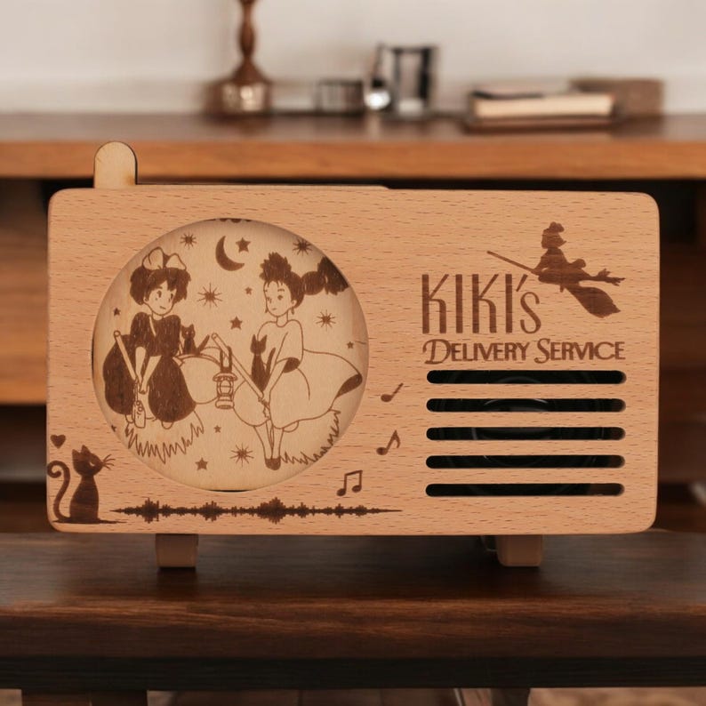 May include: A wooden music box with a laser-engraved image of Kiki and Jiji from Kiki's Delivery Service. The music box has a speaker grill and the text "Kiki's Delivery Service".