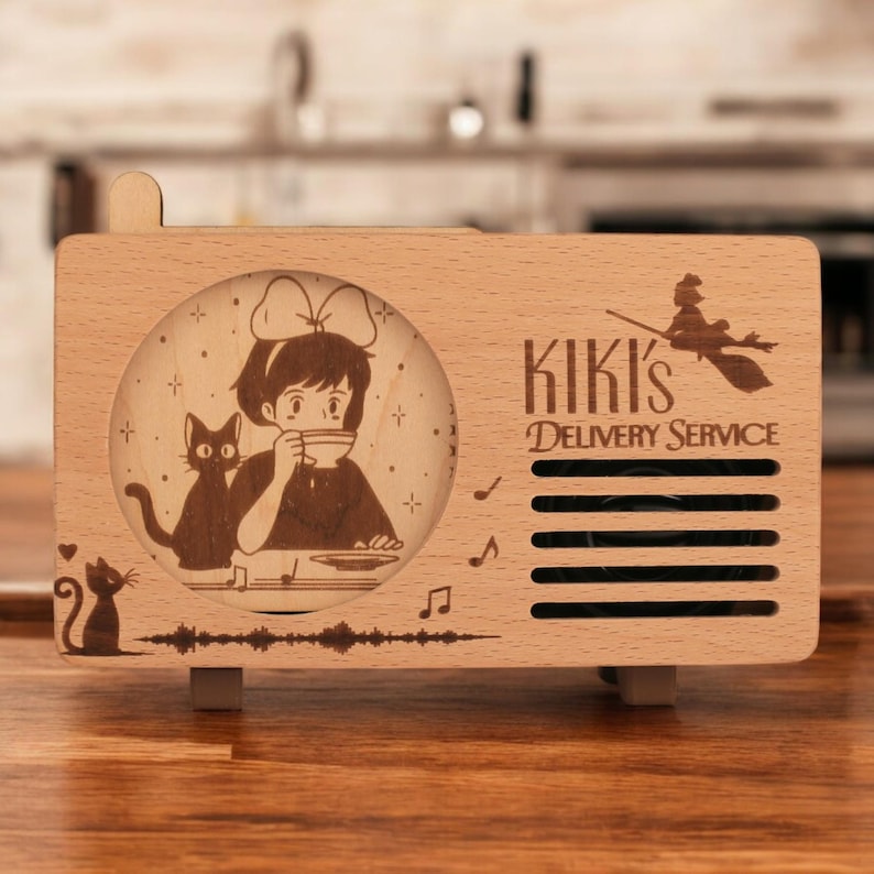 May include: A wooden music box shaped like a vintage radio with a laser-engraved image of Kiki from Kiki's Delivery Service, her cat Jiji, and the text "Kiki's Delivery Service".