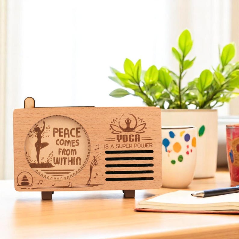 K&ouml;nnte beinhalten: Ein Holzlautsprecher mit einer hellen Holzoptik. Der Lautsprecher hat einen Ausschnitt mit einer Frau, die Yoga macht, mit dem Text "Peace comes from within" und "Yoga is a super power".