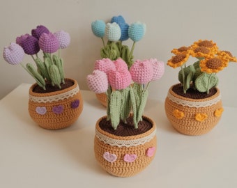 May include: Four crocheted flower pots with different colored flowers. The pots are all brown and have a white lace trim. The flowers are pink, purple, blue, and yellow.