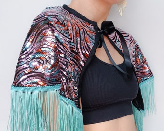 Peacock feather pattern sequinned cape with blue fringing and black ribbon fastening