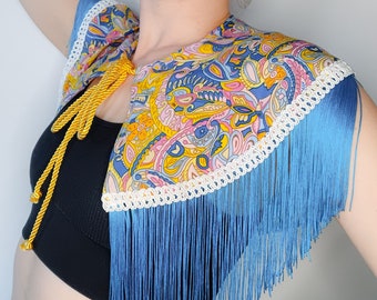 Blue, pink, and yellow retro fabric capelet with blue fringing, white trim, and gold cord fastening