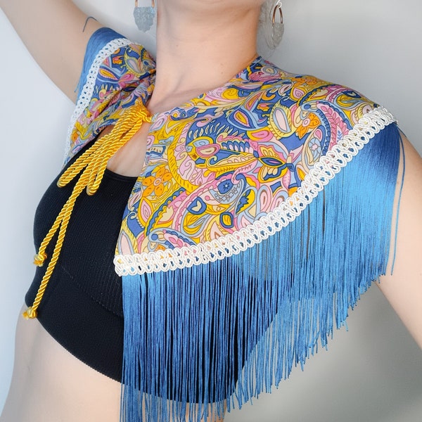 Blue, pink, and yellow retro fabric capelet with blue fringing, white trim, and gold cord fastening