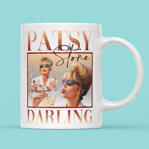 May include: White ceramic mug featuring a vintage-style image of a woman with blonde hair and sunglasses drinking from a bottle. The text "PATSY Stone DARLING" is printed on the mug.