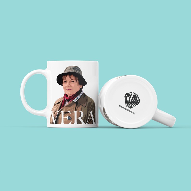 Peut inclure: Une tasse en c&eacute;ramique blanche avec une illustration en couleur de Vera Stanhope de la s&eacute;rie t&eacute;l&eacute;vis&eacute;e Vera. La tasse porte le mot "VERA" imprim&eacute; en lettres noires sur le devant.