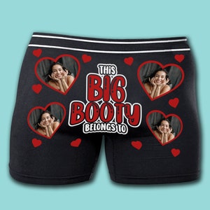 May include: Black boxer shorts with a red heart pattern and the text "This Big Booty Belongs To" in red. The boxer shorts have a white waistband and four red hearts with a photo of a person in each heart.
