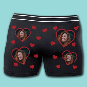 May include: Black boxer shorts with a red heart pattern and a photo of a person in each heart.