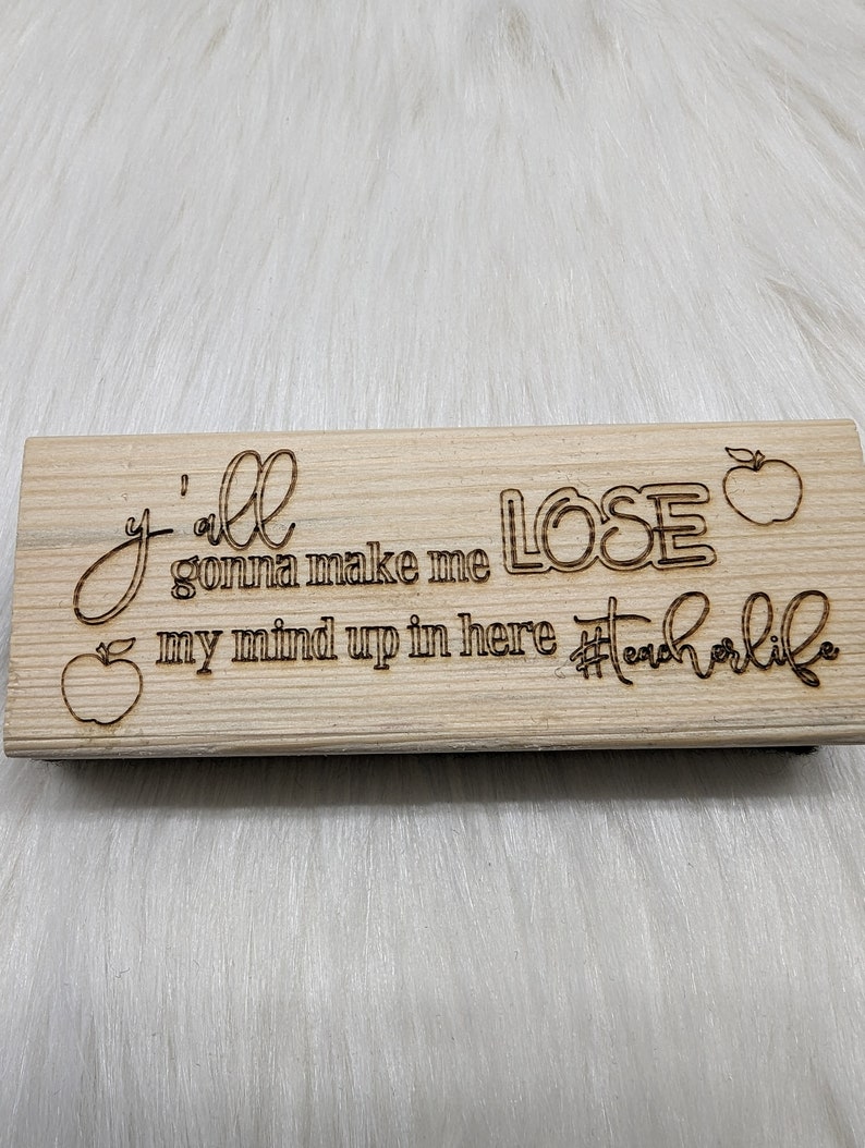 May include: Wooden sign with the text "Y'all gonna make me lose my mind up in here #teacherlife" with a red apple graphic on each side.