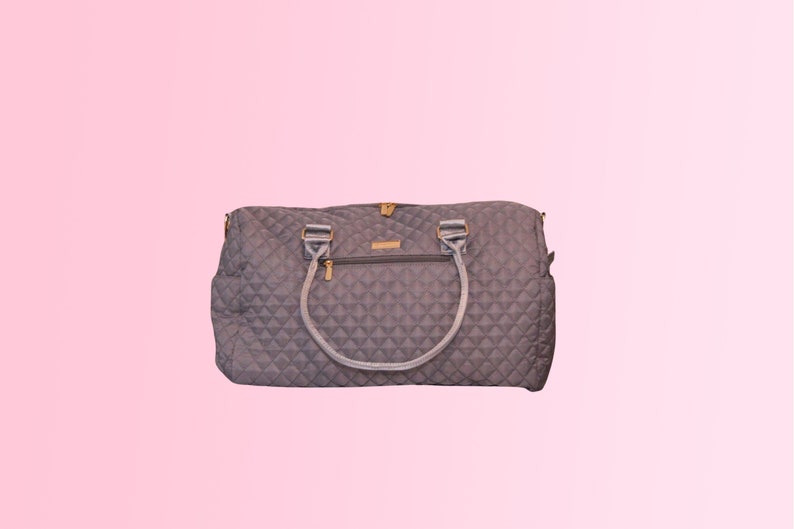 May include: A gray quilted travel bag with a gold zipper and two handles.
