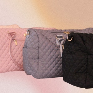 May include: Three quilted tote bags in different colors: pink, gray, and black. Each bag has a top zipper closure, two top handles, and a detachable shoulder strap.