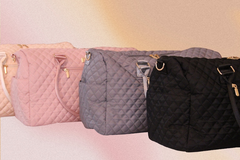 May include: Three quilted tote bags in different colors: pink, gray, and black. Each bag has a top zipper closure, two top handles, and a detachable shoulder strap.