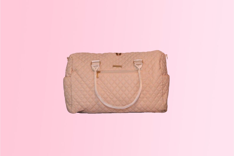 May include: A quilted cream-colored travel bag with white handles and gold accents.
