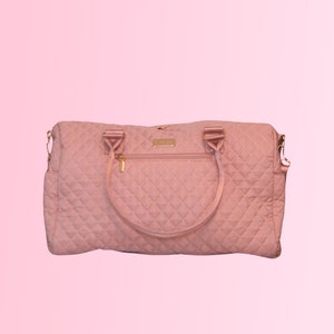 May include: A quilted pink travel bag with gold hardware and a zippered pocket on the front.