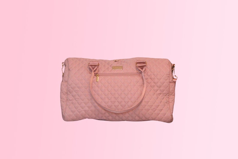 May include: A quilted pink travel bag with gold hardware and a zippered pocket on the front.
