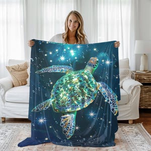 May include: A blue fleece throw blanket with a green and gold sea turtle swimming in a starry night sky.