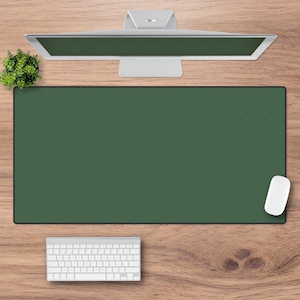 Op de afbeelding: Een groene bureau mat met een golfpatroon. De mat ligt op een houten bureau met een computermonitor, toetsenbord en muis.