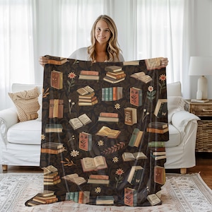 May include: A soft, brown throw blanket with a repeating pattern of books, flowers, and vines. The blanket is made of a plush, comfortable material and features a vintage aesthetic.