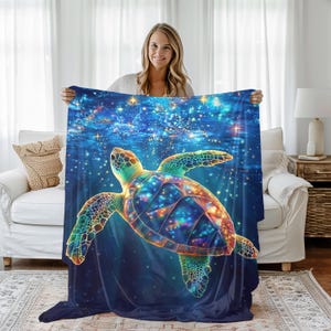 May include: A colorful sea turtle with a galaxy pattern swims through a blue and starry ocean. The turtle is surrounded by a swirling galaxy of stars and nebulae. This design is printed on a soft and cozy fleece blanket.