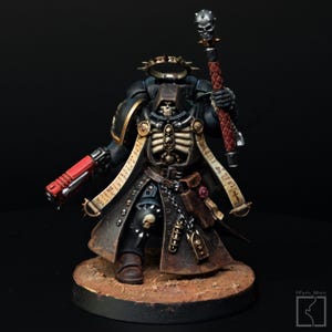 May include: A detailed miniature figure of a warrior in black armor with gold accents, a skeletal chest, and a red weapon. The figure holds a staff topped with a skull and stands on a brown base.