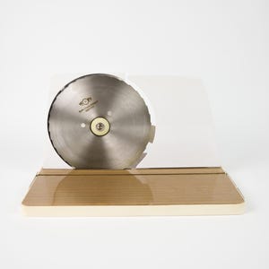 Puede incluir: Una rebanadora eléctrica blanca con una cuchilla de acero inoxidable. La rebanadora tiene una base de madera y una cubierta de plástico blanco.