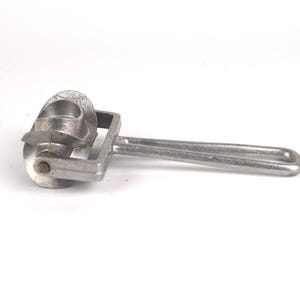Könnte beinhalten: Ein silberner Metall-Teigroller mit einem dekorativen Design. Der Roller hat einen Griff und ein Rad mit einem Muster.