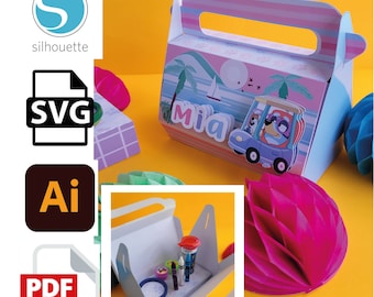May include: A blue and pink favour box with a cartoon dog driving a car. The box has a handle and says "Mia" on the front. The box is open and filled with small items.