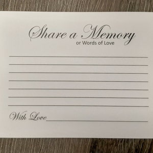 May include: White card with black text that reads "Share a Memory or Words of Love". The card has lined spaces for writing and a space at the bottom for a signature with the words "With Love".