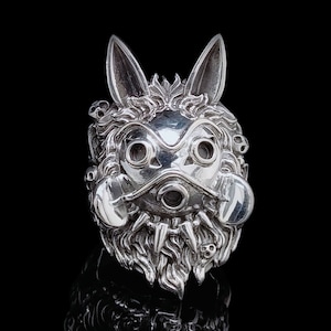 以下が含まれることがあります： 大きな耳、マスクのような顔、ひげを持つ、様式化された生き物を特徴とする詳細なシルバーリング。 リングは頭蓋骨と複雑なディテールで装飾されており、ユニークでゴシックな美学を作り出しています。