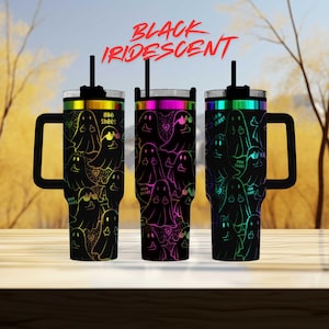 three colorful tumblers with a ghost pattern design, set against a blurred background of trees.