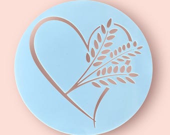 May include: A light blue plastic stencil with a heart shape and a wheat stalk design. The stencil is perfect for decorating cakes, cookies, and other baked goods.
