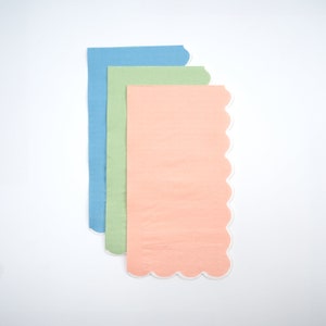 May include: Three scalloped-edge paper napkins in blue, green, and peach colors.