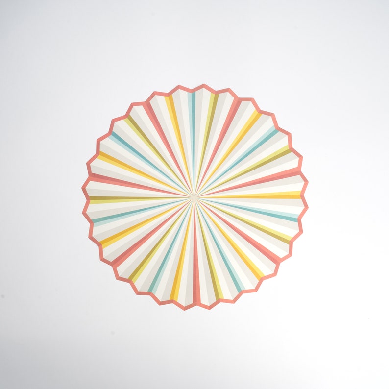 May include: A colorful, circular design with radiating stripes in shades of pink, yellow, blue, and green. The design has a starburst effect, creating a sense of movement and energy.