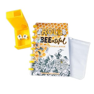 May include: A yellow dice cup with two dice showing the numbers 2 and 5, a spiral-bound savings challenge notebook with the text "Roll the Dice BEEutiful Savings Challenge", and a clear plastic pouch. The notebook features a bee graphic and a honeycomb design.