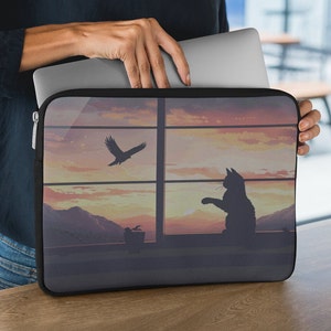 May include: Black laptop sleeve featuring a sunset scene with a cat looking out of a window at a bird flying away. The sleeve has a zipper closure.