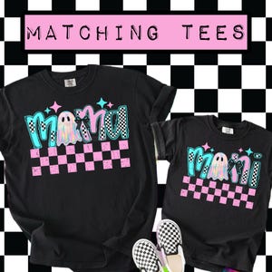 May include: Black t-shirts with the words "Mama" and "Mini" in a teal and pink checkered design, with a ghost graphic. The text "Matching Tees" is in a pink rectangle above the shirts. A pair of black and white checkered slip-on shoes are at the bottom.