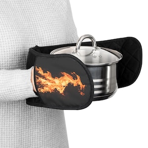 May include: Black pot holders with a flame design are wrapped around a stainless steel pot with a glass lid. The pot holders are black with a quilted pattern on the back. The flame design is orange and yellow.