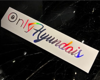 Puede incluir: Una pegatina rectangular blanca con las palabras "only Hyundais" en una fuente de gradiente arcoíris. La palabra "only" tiene un símbolo de ojo negro. La pegatina está sobre una superficie negra reflectante.