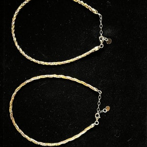 Op de afbeelding: Twee gevlochten kettingen van goud en zilver met een karabijn sluiting.
