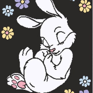 May include: A white bunny with closed eyes is curled up in a sleeping position. The bunny is surrounded by colorful flowers with pink, yellow, blue, and purple petals.