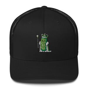 May include: Black trucker hat featuring an embroidered cartoon pickle wearing a crown and holding a scepter. The pickle is green with white accents, and the crown and scepter are gold. The hat has a mesh back and a curved brim.