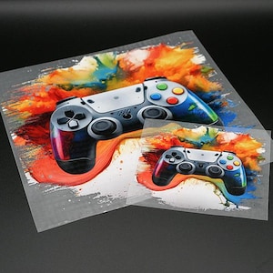 Könnte beinhalten: Zwei Gamecontroller-Designs auf einem transparenten Blatt. Die Controller verfügen über ein farbenfrohes, abstraktes Farbspritzer-Design mit roten, orangen, gelben, blauen und grünen Farbtönen. Die Controller haben schwarze Knöpfe und graue Gehäuse.