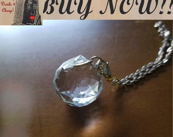 Op de afbeelding: Een heldere kristallen hanger met een zilveren ketting. De hanger is gefacetteerd en reflecteert licht. De ketting is zilver en heeft een karabijnhaak.