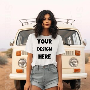 May include: A woman wearing a white t-shirt with the text "YOUR DESIGN HERE" printed on it. She is standing in front of a white van.