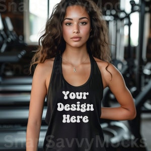 May include: A black racerback tank top with the text "Your Design Here" in white, retro-style lettering. The tank top is being worn by a person with long, curly brown hair in a gym setting.