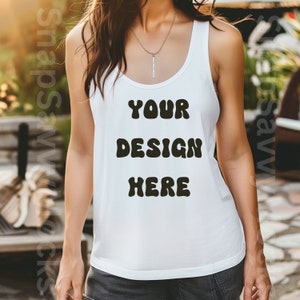 Puede incluir: Un top blanco de tirantes con el texto "YOUR DESIGN HERE" en letras negras de estilo retro. El top está siendo usado por una persona.