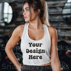 Może przedstawiać: Biały top na ramiączkach z napisem "Your Design Here" w kolorze czarnym, noszony przez osobę z długimi blond włosami. Top jest krótki i ma okrągły dekolt.